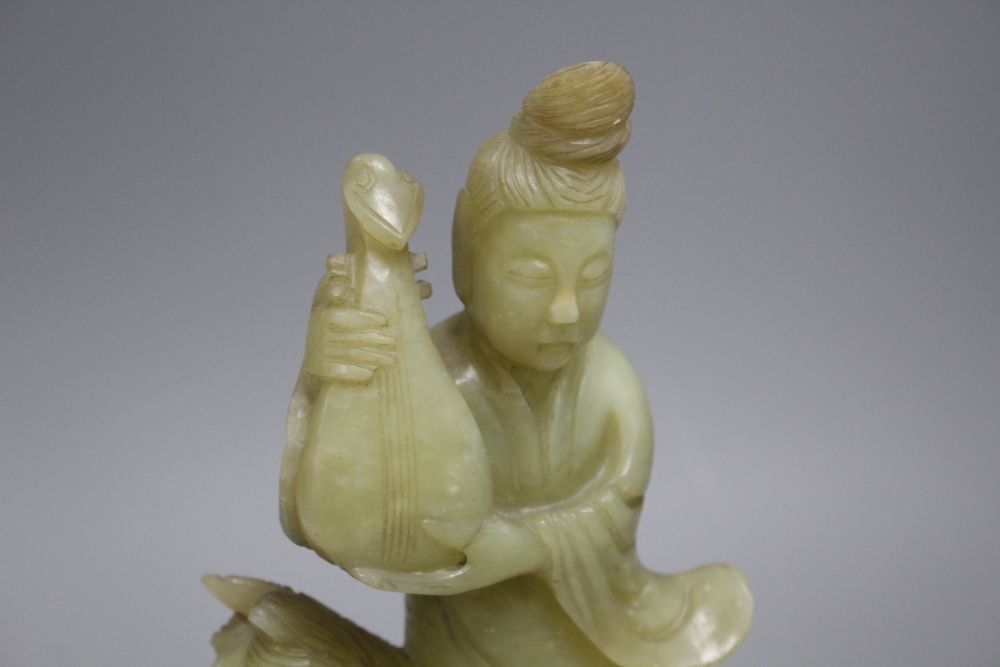 A pair of Chinese bowenite jade groups of a lady riding a horse, wood stands total height 26.5 and 27cm